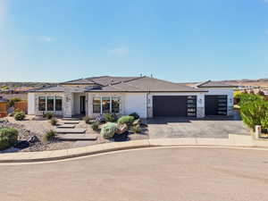 Prairie-style house featuring stone siding, an attached garage, asphalt driveway, and stucco siding