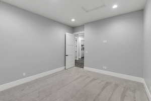 Unfurnished room with light colored carpet, recessed lighting, and attic access