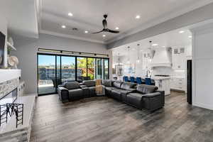 Living room featuring ornamental molding, dark wood-style flooring, recessed lighting, a fireplace, and ceiling fan