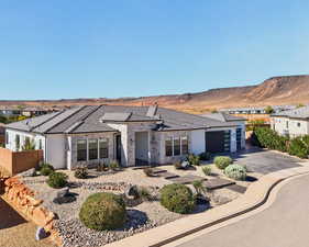 View of front of house with stone siding, stucco siding, driveway, and a patio