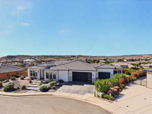View of front of property with a residential view, an attached garage, driveway, and stone siding