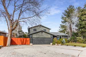 View of front facade featuring driveway, a 2 car garage, fenced yard, new roof, new siding with stone and  brick.