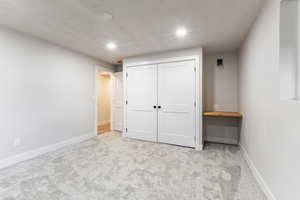 Unfurnished bedroom with light colored carpet, a closet, and recessed lighting