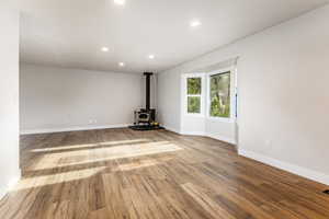Living room featuring a wood stove, LVP floors, and recessed lighting with a bay window.