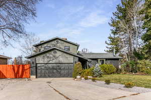 View of front facade featuring driveway, a 2 car garage, fenced yard, new roof, new siding with stone and  brick.