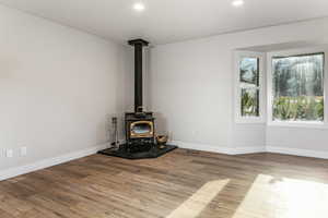 Living room featuring a wood stove, LVP floors, and recessed lighting with a bay window.