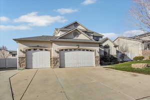 View of front facade with stucco siding, a garage, concrete driveway, and stone siding