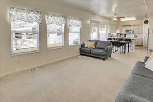 Living room featuring light colored carpet and a ceiling fan
