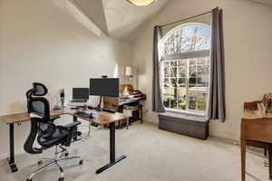 Office with high vaulted ceiling and light colored carpet
