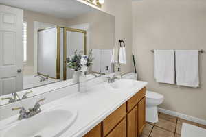 Bathroom with double vanity, light tile patterned floors, a shower stall, and a garden tub