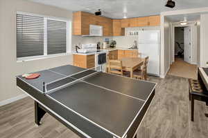 Recreation room with a textured ceiling and light wood-style floors