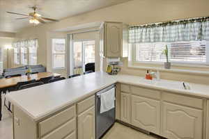 Kitchen featuring open floor plan, light countertops, stainless steel dishwasher, a peninsula, and a ceiling fan