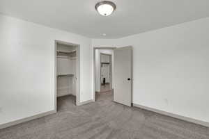 Unfurnished bedroom with a spacious closet and carpet floors