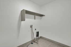 Washroom with hookup for a washing machine, light tile patterned floors, and hookup for an electric dryer