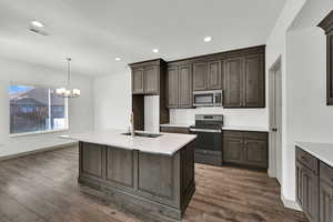 Kitchen with stainless steel appliances, decorative light fixtures, a kitchen island with sink, recessed lighting, and a chandelier