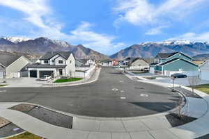 View of asphalt road with sidewalks, a residential view, a mountain view, and curbs