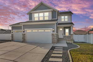 View of front of property with stone siding, concrete driveway, a gate, a garage, and a shingled roof