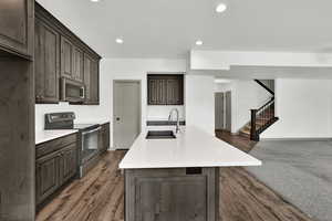 Kitchen with stainless steel appliances, dark brown cabinetry, a kitchen island with sink, recessed lighting, and open floor plan