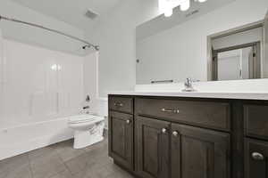 Bathroom featuring vanity, shower / bath combination, and light tile patterned floors