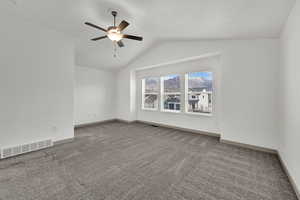 Empty room featuring light carpet, lofted ceiling, and ceiling fan