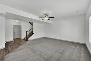 Unfurnished living room with stairway and a ceiling fan