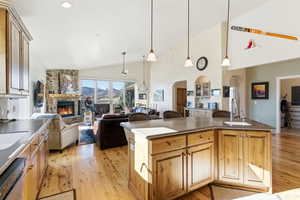 Kitchen featuring a fireplace, light wood-type flooring, hanging light fixtures, dishwashing machine, and open floor plan