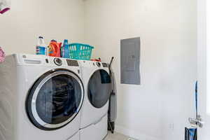 Washroom with electric panel, washer and clothes dryer, and tile patterned flooring