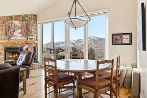 Dining area with a mountain view, light wood-style floors, vaulted ceiling, and a fireplace