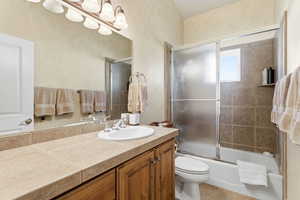 Bathroom featuring vanity, combined bath / shower with glass door, and tile patterned floors