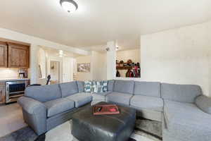 Carpeted living area with wine cooler, stairs, and a bar