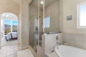 Ensuite bathroom featuring plenty of natural light, tile patterned flooring, a bath, and a stall shower