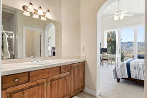Ensuite bathroom with vanity, light colored carpet, ceiling fan, and an enclosed shower