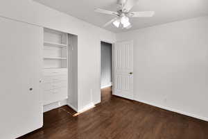 Unfurnished bedroom featuring ceiling fan, dark wood-type flooring, and a closet