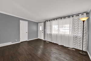 Spare room featuring ornamental molding and dark wood-type flooring