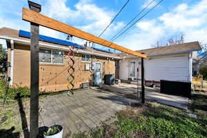 Rear view of property featuring a patio, entry steps, and roof mounted solar panels