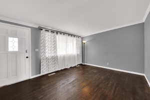 Foyer with ornamental molding and dark wood-style floors