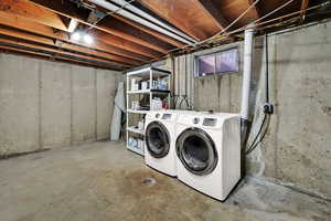 Laundry area with unfinished concrete flooring and washer and clothes dryer