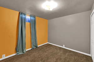Empty room with dark colored carpet and baseboards