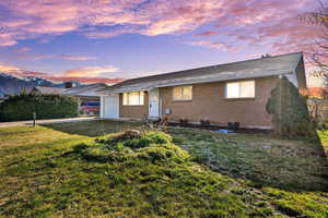 Ranch-style home with an attached garage, a yard, roof with shingles, and brick siding