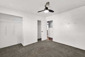 Unfurnished bedroom featuring two closets, dark carpet, and a ceiling fan