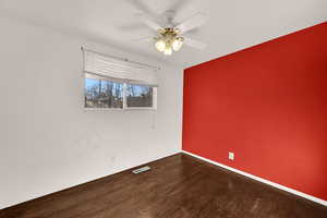 Empty room featuring dark wood-type flooring and a ceiling fan