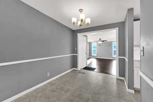 Unfurnished dining area with a chandelier and a ceiling fan