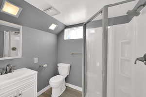 Full bath with a stall shower, vanity, wood finish floors, and lofted ceiling