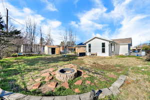 View of grassy yard featuring a trampoline, a storage shed, a fire pit, and a patio