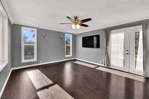 Empty room with crown molding, dark wood-type flooring, a ceiling fan, and french doors