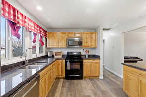 Kitchen featuring appliances with stainless steel finishes, dark stone counters, and light brown cabinets