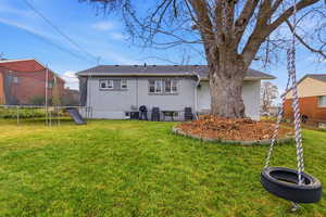 Back of property featuring a trampoline and brick siding