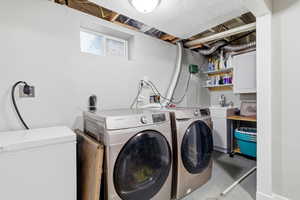 Laundry area featuring concrete flooring, washing machine and clothes dryer, and cabinet space