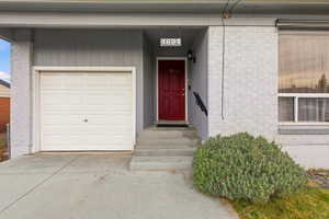 Doorway to property featuring concrete driveway and a garage