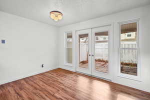 Spare room with wood finished floors, a textured ceiling, and french doors